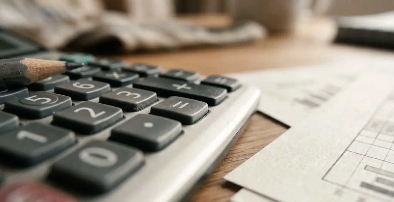 Vue en plongée sur un espace de travail avec calculatrice et documents de planification budgétaire pour travaux de rénovation